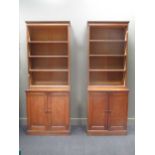 Two similar Edwardian oak open bookcases above cupboard bases, 220cm high, one 86cm wide, the