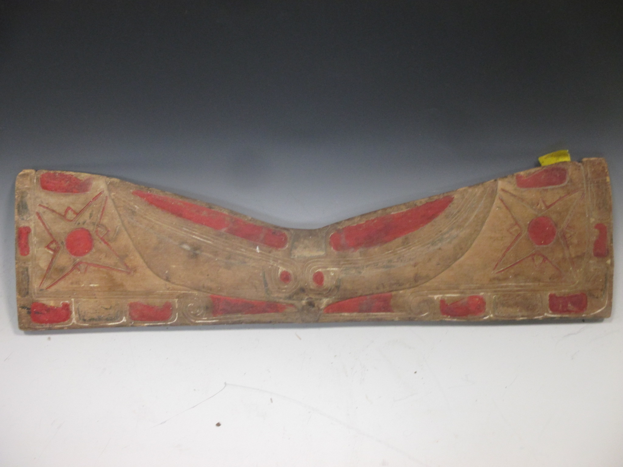 A North American Indian carved and painted pine rest panel, carved in low relief with a stylized