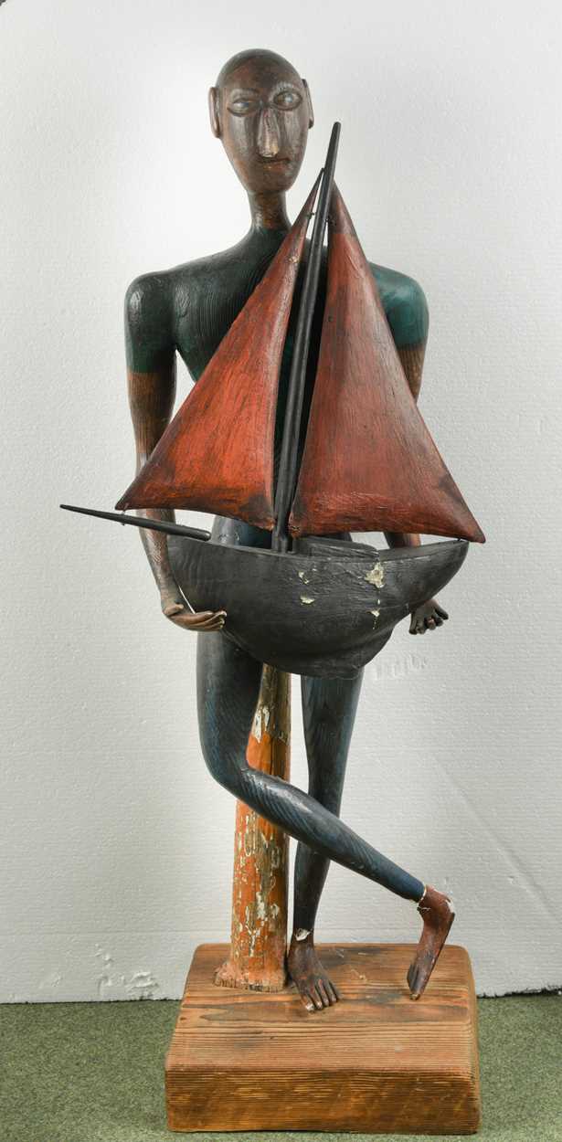 A wood and plaster figure of standing ethnic man holding a pond yacht, 109cm tall