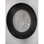 A pair of black lacquered wall brackets and an oval plaster classical plaque