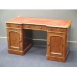 A Victorian walnut kneehole desk with inverted breakfront red leather top, three drawers over two