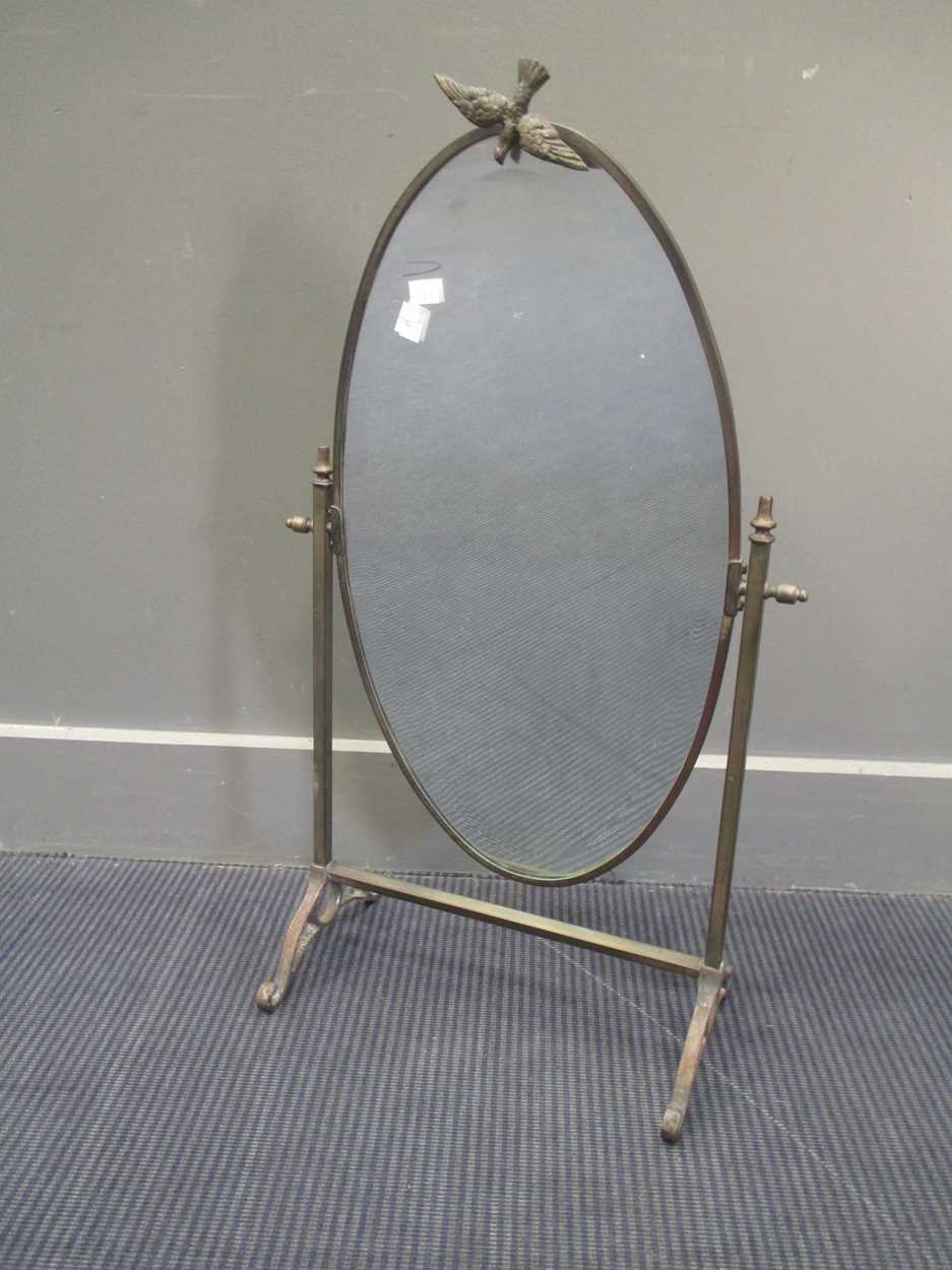 A brass framed oval dressing table mirror, with dove cresting 75cm high 44cm wide