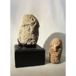 A carved tufa primitive head, perhaps early Chinese, and another smaller example, 21cm and 17cm (2)