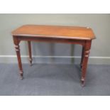 A mahogany canted rectangular side table on turned legs with castors 74 x 106 x 55cm