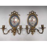 A pair of early 20th century gilt metal and 'Sevres' porcelain twin-branch wall sconces