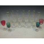 A set of seven glass flutes, two pairs of coloured bowl glasses, other drinking glasses and a