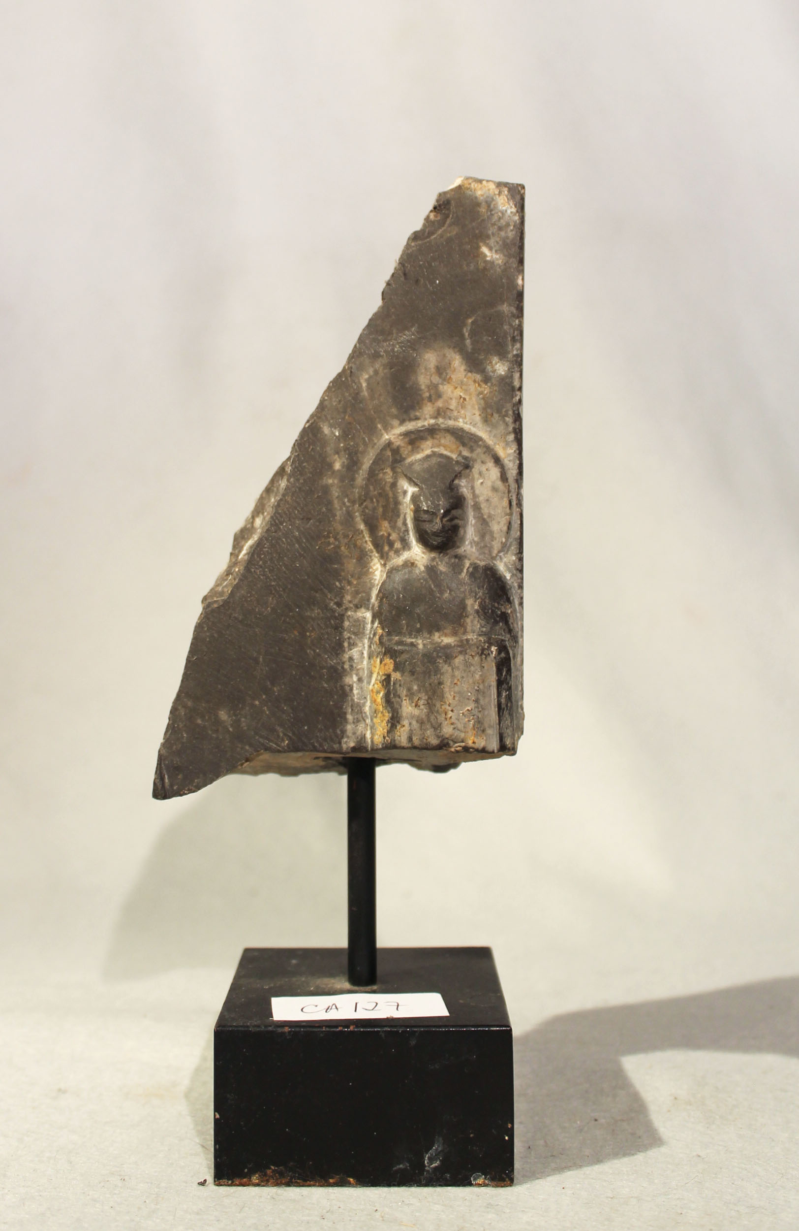 A Chinese black stone stele fragment carved with a Buddhist disciple, in Wei Dynasty style, 17.5cm