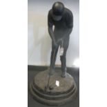A cast iron figure of a golfer putting, on stepped base