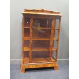 A Biedermeier style walnut display cabinet with angular moulded cornice enclosed by a glazed door, a