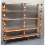 A large open bookcase of five shelves on pine baluster supports. 205cm high by 216cam wide by 45cm