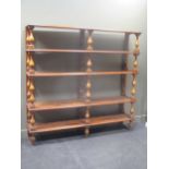A large open bookcase of five shelves on pine balustor supports. 205cm high by 216 cms wide by