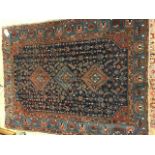 A dark blue ground rug with 3 central lozenges, dark red spandrels and blue patterned main border,