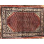 A Sarab small red ground rug with multiple gul field, and main patterned cream border, 150 x