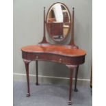 An Edwardian flame mahogany kidney shape dressing table, the oval tilting bevel edge mirror and