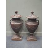 A pair of modern reproduction bronze urns with covers, on square bases approx 97cm high and 47cm