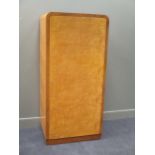 A 20th Century continental burr maple wardrobe with curved top, enclosed by a panel door on a plinth