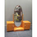 An Art Deco burr walnut pedestal dressing table with scroll supports for an oval mirror flanked by