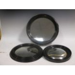 Two small ebonised frame convex wall mirrors; and another circular mirror (3)