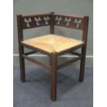 A Gothic revival oak corner chair with rush seat