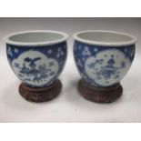 A modern pair of Chinese blue and white planters on carved wooden stands