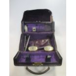 A purple leather travelling cosmetic case by Asprey, with two silver topped glass bottles together