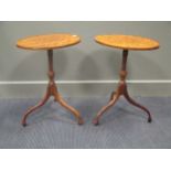 A pair of small George III style occasional tables, with oval cross banded tops on three splayed