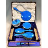 A George V silver and enamel 7 piece dressing table set with one addition,