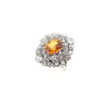 An orange sapphire and diamond cluster ring,