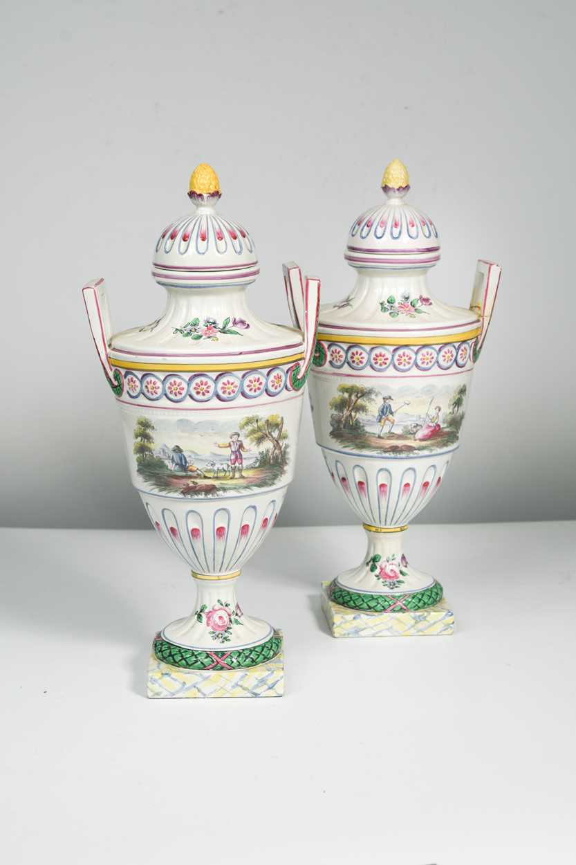 A pair of continental faience two-handled vases and covers, decorated with vignettes of a couple