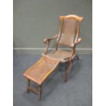 An Edwardian teak folding garden chair with caned back, seat and foot rest