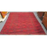 An Afghan carpet woven in the traditional colours on a red ground with three rows of seven