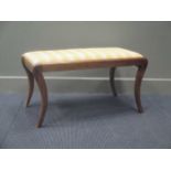 A 19th century mahogany footstool on four sabre legs, with a stripe upholstered drop in seat 45 x 86