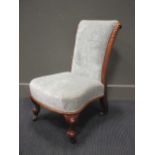 A mid Victorian carved walnut low chair on scroll feet and ceramic castors