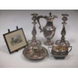 A pair of plated candlesticks with floral and c scroll decoration 27 cm high, a hot water jug with