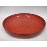 A large red painted wooden platter, 53cm diameter
