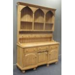 A pine kitchen dresser, the top section with triple arch fronted plate rack above three drawers, the