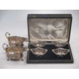 A pair of early 20th century silver cream jugs and a cased set of four silver bon bon dishes