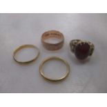 A collection of four rings including a hallmarked 9ct gold ring, a garnet ring tested as 9ct gold