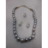 A string of grey baroque pearls together with a matching pair of earrings and pendant (3)