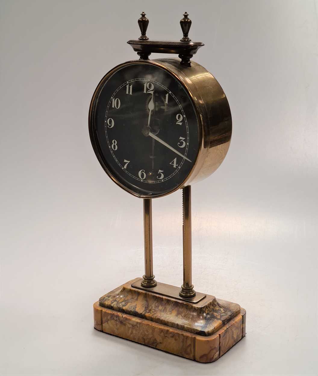 A British made gravity clock with 10cm dial, lacquered brass case on marble base, 26cm