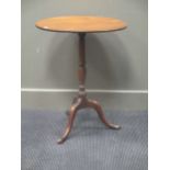 A George III mahogany tilt top tripod table, the circular top on a turned column support with