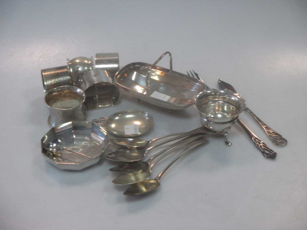 A collection of silver wares including napkin rings, flatware, a miniature trug and a continental
