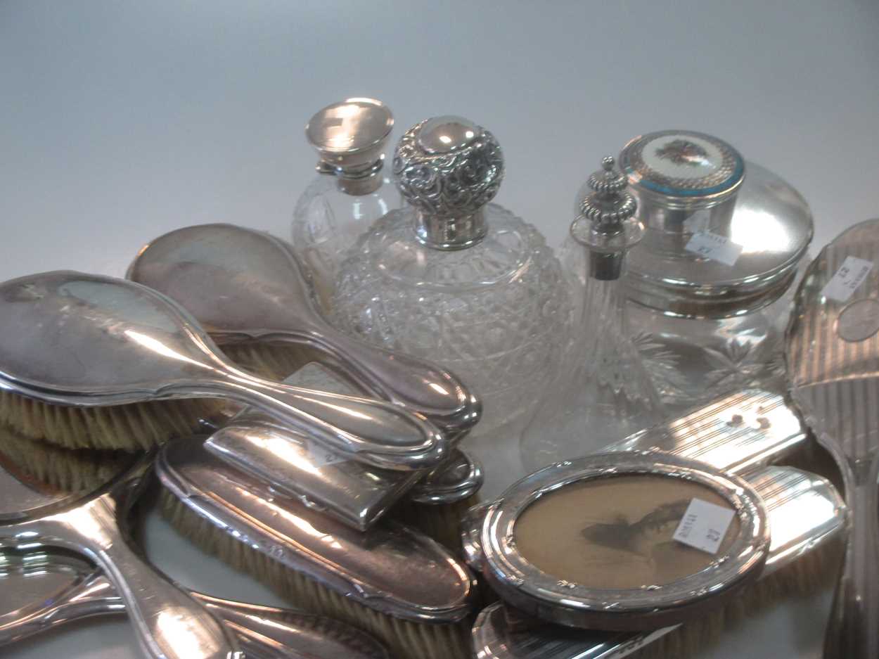 A collection of silverware including silver backed dressing table items, silver topped glass perfume