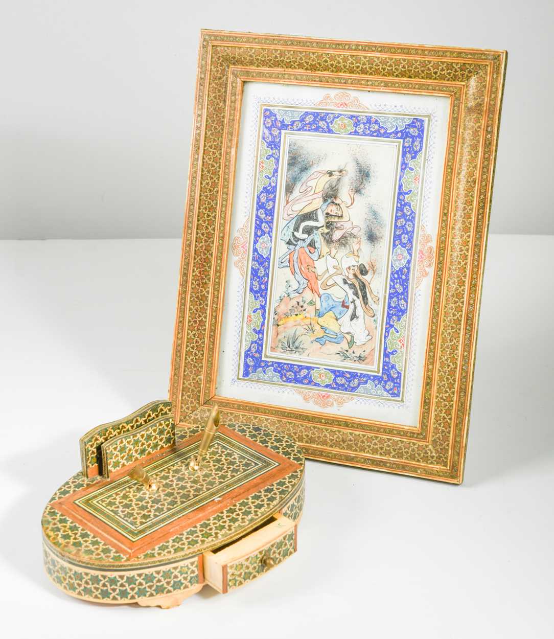 An Islamic goauche courtship scene in an elaborate inlaid frame and matching inlaid inkstand,