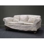 An Edwardian three seater sofa raised on bun feet and castors, total width 180cm