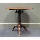 A George III mahogany tripod table with bird cage support, above a turned baluster column on