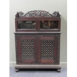 A 19th century Anglo-Indian heavily carved chiffonier with glazed upper section above a pair of fret
