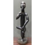 A 20th century African carved figure of seated male smoking a pipe, mirror insert to the side of the