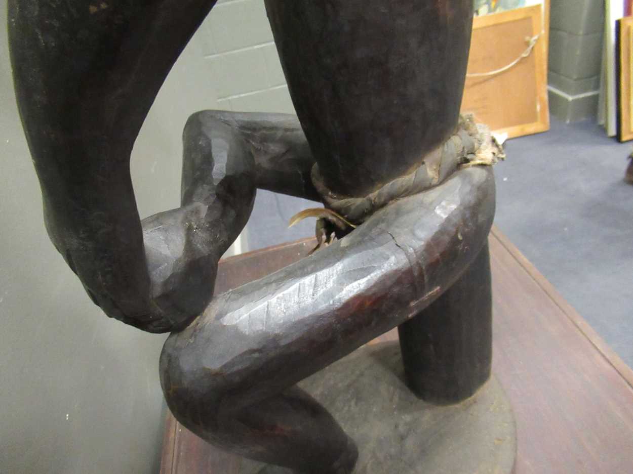 A 20th century African carved figure of seated male smoking a pipe, mirror insert to the side of the - Image 7 of 9