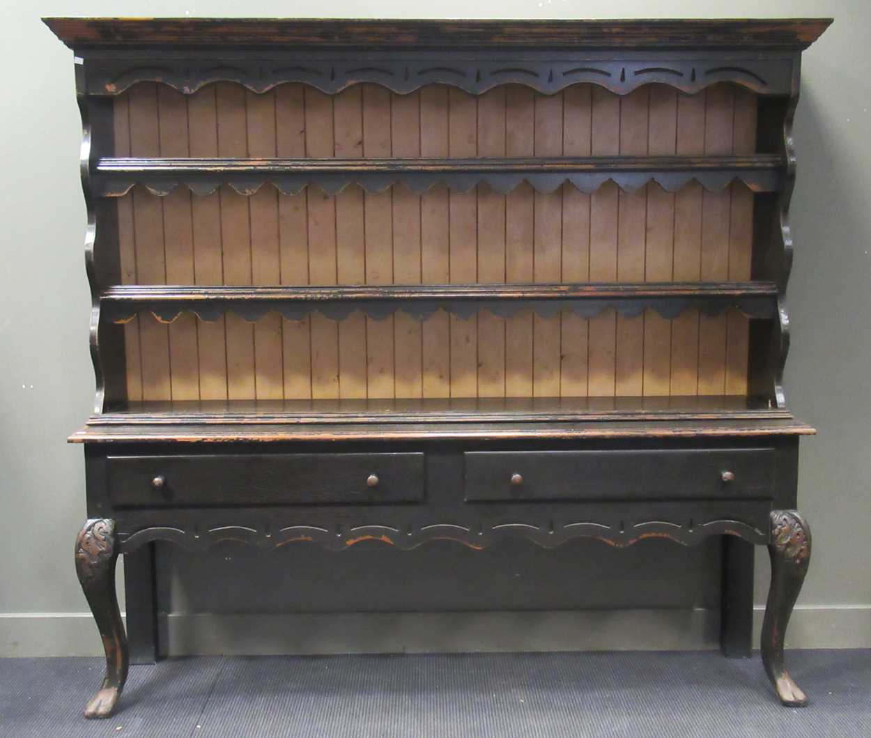 A black painted dresser, with two shelved plate rack above two long drawers on cabriole front legs